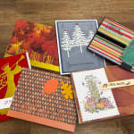 Assorted handmade greeting cards with fall and Christmas designs on a wooden surface