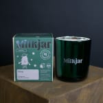 Green scented candle in a glass jar beside its box
