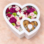 Heart-shaped flower box with pink, white, and magenta blooms and gold chocolates
