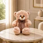 Plush teddy bear with a checkered bow sitting on a round table