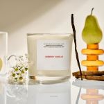 Vanilla candle in a glass jar with small white flowers beside it