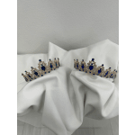 Two jeweled blue tiaras resting on white fabric.