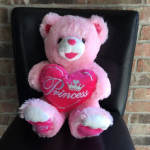 Pink teddy bear holding a heart-shaped pillow