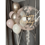Birthday balloon cluster with a clear balloon and pastel balloons