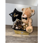 Detail of a large bear, a Ferrero box, a balloon with the phrase "love," and a golden box.