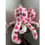 Two pink spotted plush octopuses on a small wooden table