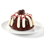 Chocolate bundt cake with white icing and red drizzle on a white plate