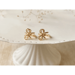 Pair of gold bow-shaped earrings on a white plate