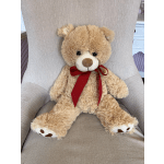 Plush teddy bear with a red ribbon sitting on a chair