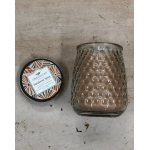Glass candle jar with a patterned lid beside a matching candle tin