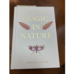 Hardcover book titled Magic in Nature with gold text and a pink insect illustration on a wooden surface