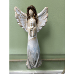 Ceramic angel figurine with outstretched wings on a green wall