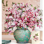 Pink and white blossoms arranged in a decorative green vase with a matching card