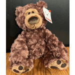 Brown plush teddy bear sitting on a wooden surface with a tag attached