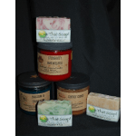 Assorted handmade soap bars and jars stacked on a dark background