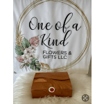 Orange chocolate gift box on white fur in front of a floral One of a Kind Flowers & Gifts sign