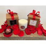 Gift set with two ribbon-tied candle boxes, a glass candle, and a chocolate truffle on rose petals.