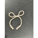 Pearl bead bow accessory on a dark textured surface