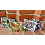 Four floral art cards leaning against a brick wall