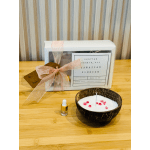 Candle making kit with boxed set, coconut shell candle bowl, and small fragrance dropper bottle on wood table