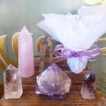 Crystal points and a wrapped purple gift bundle on a wooden surface