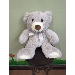 Gray teddy bear with a ribbon sitting on a small stand