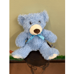 Blue teddy bear with a ribbon sitting on a stand