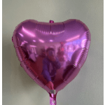 Pink heart-shaped foil balloon against a plain wall