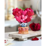 Mini koala figurine in a basket with red and pink heart balloons, styled beside a red rose.