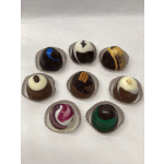 Assortment of eight decorated round chocolate truffles in paper cups on a white surface