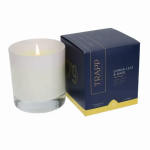 White candle in a glass jar beside a navy candle box