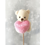 Small cream teddy bear holding a pink heart that says Thank you on a stick