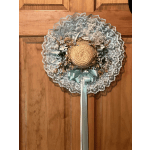 Round decorative wreath with lace trim, ribbon, and small flowers on a wooden door