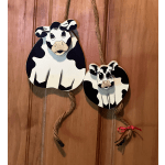 Two cow-shaped hanging decorations on a wooden door