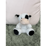 Plush cow toy sitting on a shaggy rug in front of a pale pillow