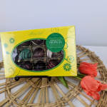 Box of truffles beside orange tulips on a woven mat