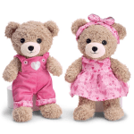 Two teddy bears in pink outfits, one in overalls and one in a dress