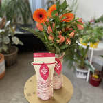 Orange gerbera daisies and peach tulips in a branded flower food pouch