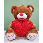 Brown teddy bear holding a red heart-shaped floral decoration