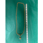 Gold chain necklace with a small heart pendant beside a measuring tape