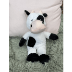 Plush cow toy sitting on a fuzzy rug in front of a pillow