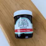 Jar of blueberry jam with a white lid on a wooden surface