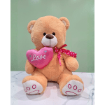 Plush teddy bear holding a pink heart with the word Love