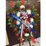 Large standing floral wreath with red, white, and blue flowers and a ribbon