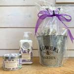 Gift set with lavender candle, lotion, and a flower garden bucket wrapped in purple ribbon
