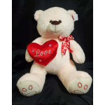 Large white teddy bear holding a red heart pillow with a ribbon