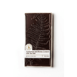 A dark chocolate bar in a white wrapper with cardamom and honey caramel labeling