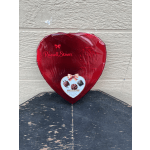 Red heart-shaped box of assorted chocolates on a worn black table