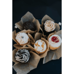 Six frosted cupcakes wrapped in brown paper cups