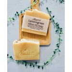 Two beige lemongrass olive oil soap bars on a wooden board with a trailing vine accent.